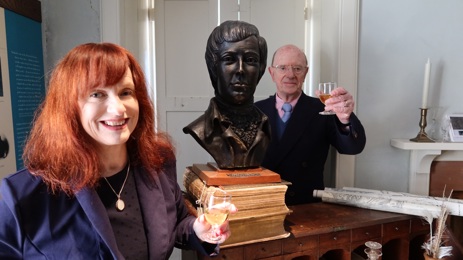 Man and woman with a dram of whisky alongside bust of Robert Burns